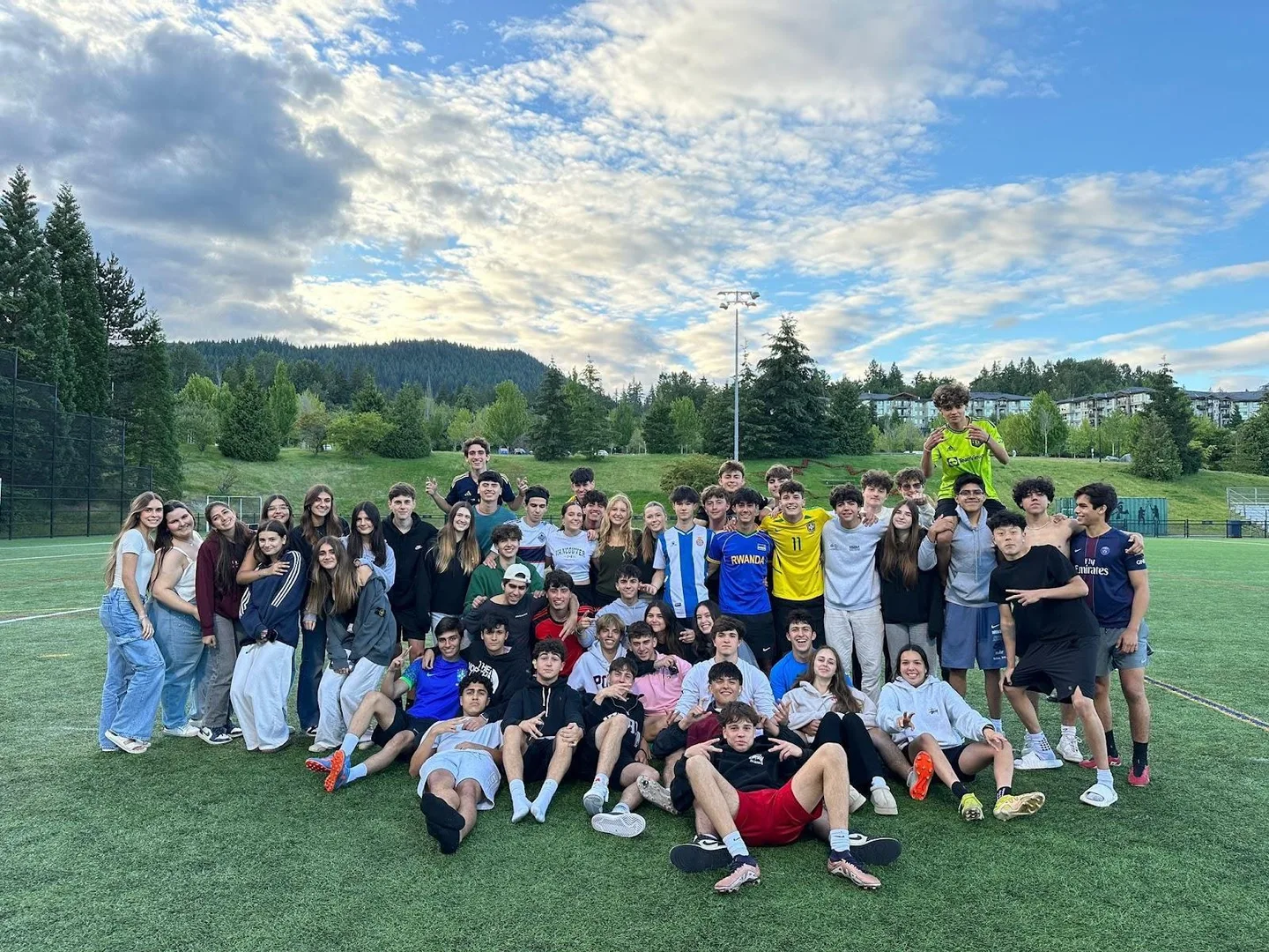 Grand groupe d'élèves sur un terrain de sport à Comox, forêt canadienne en arrière-plan